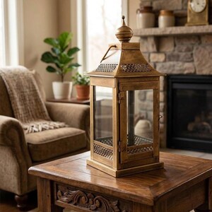 Puede incluir: Un farol rectangular alto con acabado dorado envejecido, que presenta paneles de vidrio transparente en todos sus lados, una puerta abatible con pestillo y un techo met&aacute;lico decorativo con remate en punta y calados intrincados en la base.
