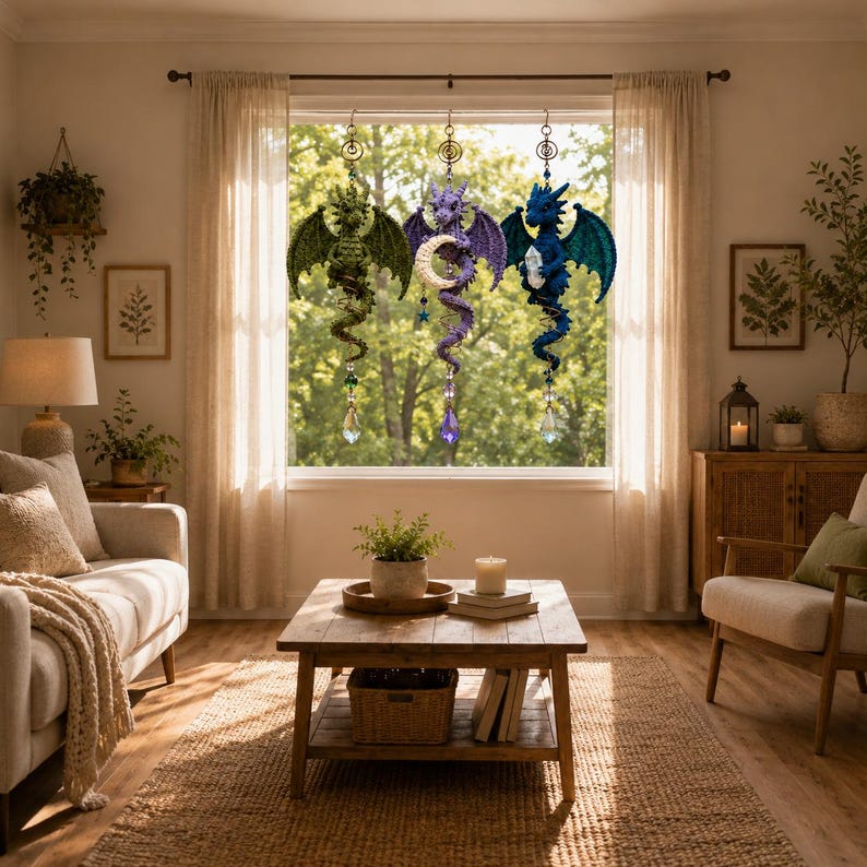 May include: Three hanging crochet dragon ornaments in green, purple, and blue, each featuring a coiled tail, textured wings, and a dangling crystal prism. The purple dragon holds a crescent moon, while the blue dragon holds a clear crystal.