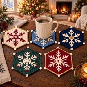 May include: A set of five hexagonal crochet coasters featuring snowflake patterns in cream, red, blue, dark blue, and green. Each coaster has small white decorative knots at the corners. A white ceramic mug sits on the blue coaster.