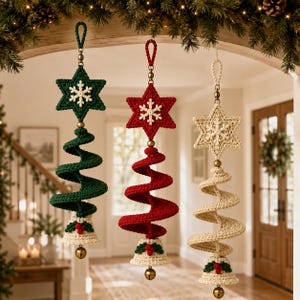 Può includere: Tre ornamenti all'uncinetto da appendere composti da una stella a sei punte con un fiocco di neve bianco, un corpo a spirale a forma di albero e una campana alla base con foglie verdi e bacche rosse. Gli ornamenti sono verde, rosso e crema.