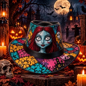 May include: A wide-brimmed hat featuring a vibrant patchwork design with teal, yellow, and pink patterns. The front displays a detailed illustration of a pale-skinned character with long red hair and stitched facial features, accented by a black band.