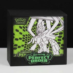 May include: Black display box featuring a Pokémon trading card game design. The box has a green and black background with a white illustration of a Pokémon character. The text "MEGA EVOLUTION PERFECT ORDER" is displayed on the front.
