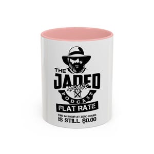 May include: White ceramic mug with a pink interior. The mug features a black graphic with the text "THE JADED MECHANIC PODCAST" and "FLAT RATE". The design includes an illustration of a man in a hat and sunglasses.