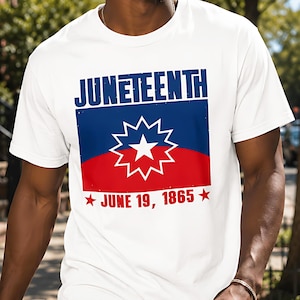 以下が含まれることがあります： 上部に青い文字でJUNETEENTH、中央に白い星をあしらった青と赤の旗のデザイン、下部に2つの赤い星を伴う赤い文字でJUNE 19, 1865とプリントされた、白い半袖Tシャツ。