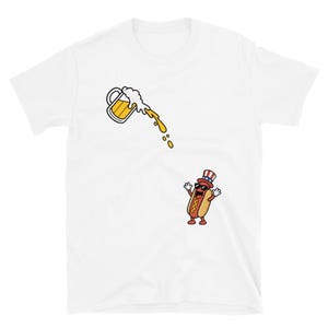May include: A white short-sleeve t-shirt featuring a graphic of a tilted beer mug pouring golden liquid downward toward a cartoon hot dog character wearing black sunglasses and a red, white, and blue striped top hat with a blue star band.