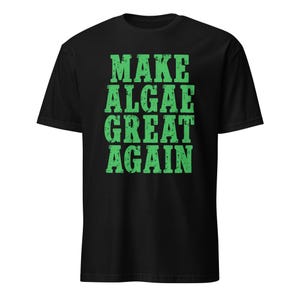 Könnte beinhalten: Ein schwarzes T-Shirt mit kurzen Ärmeln und dem Text "MAKE ALGAE GREAT AGAIN", der in einer abgenutzten, strukturierten grünen Schrift auf der Brust gedruckt ist. Das Shirt hat einen Rundhalsausschnitt und eine normale Passform.