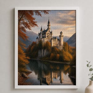 May include: A framed jigsaw puzzle depicting a large stone castle with multiple towers perched on a rocky cliff surrounded by autumn trees with orange and brown foliage, reflected in the calm water of a lake below under a soft sunset sky.