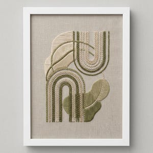 May include: A framed embroidery piece on light beige linen fabric featuring abstract shapes in shades of olive green and cream. The design includes arched lines, textured stitching, and organic leaf-like forms created with various embroidery thread techniques.