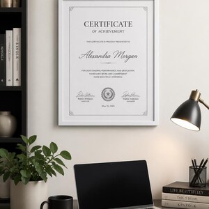 Puede incluir: Un certificado de logros enmarcado en blanco colgado en la pared, con el texto "CERTIFICATE OF ACHIEVEMENT", "Alexandra Morgan", "May 15, 2024" y las firmas de Robert Williams y Sophia Anderson, con bordes decorativos en las esquinas.