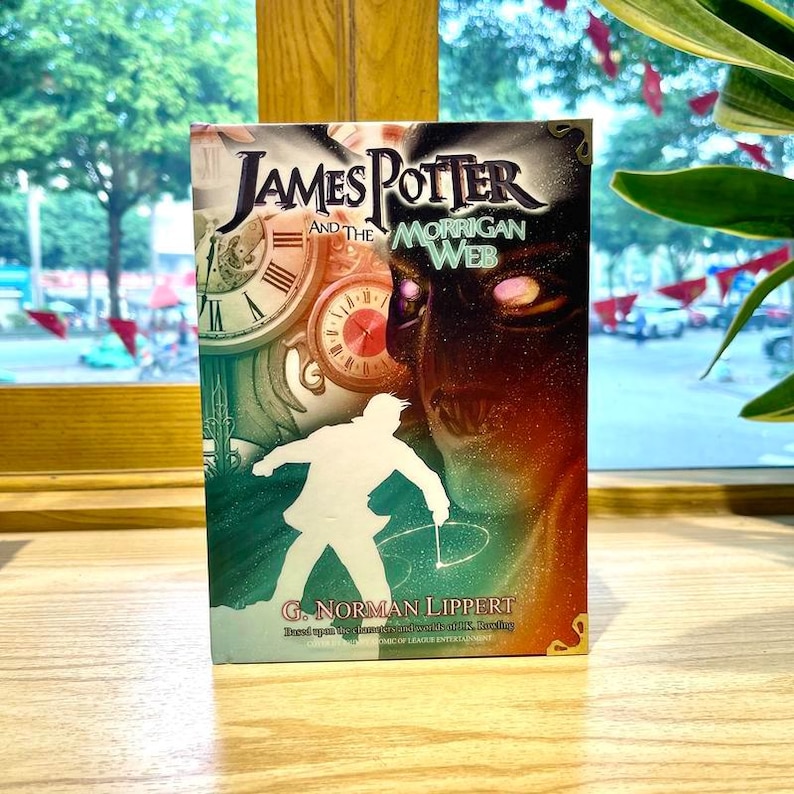 May include: A book titled James Potter and the Morrigan Web by G. Norman Lippert. The cover features a white silhouette of a person, two clock faces, and a dark, glowing face with bright eyes. The design uses shades of green, red, and black.