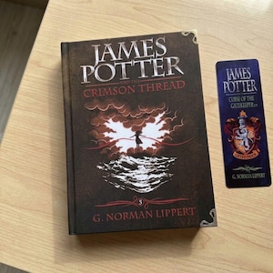 May include: A hardcover book titled James Potter and the Crimson Thread by G. Norman Lippert with a dark brown cover featuring a silhouette figure, clouds, and waves, alongside a matching rectangular bookmark with a crest and text.