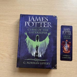 May include: A hardcover book titled James Potter and the Curse of the Gatekeeper by G. Norman Lippert with a dark blue cover featuring a green spectral figure and a matching rectangular bookmark displaying a crest and the same book title.
