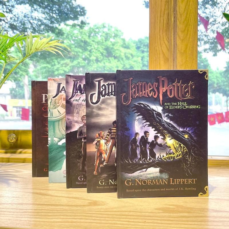 May include: A row of five fantasy books titled James Potter by G. Norman Lippert. The front book features a dark cover with a large dragon head and three figures, titled James Potter and the Hall of Elders Crossing, with gold corner accents.