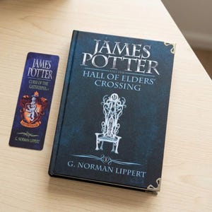 May include: A dark blue hardcover book titled James Potter and the Hall of Elders' Crossing by G. Norman Lippert with a white chair illustration and metal corner protectors, accompanied by a matching dark blue bookmark featuring a Gryffindor crest.