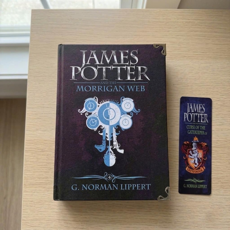 May include: A hardcover book titled James Potter and the Morrigan Web by G. Norman Lippert with a dark purple cover featuring a central clock graphic and metal corner protectors, accompanied by a matching vertical bookmark with a crest design.