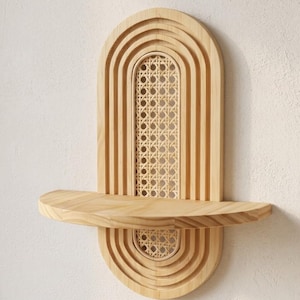 Peut inclure: Étagère murale en bois naturel avec un design en arche. L'étagère présente un panneau central en canne tressée et une étagère incurvée. Le design incorpore des arches superposées et une base en demi-cercle.