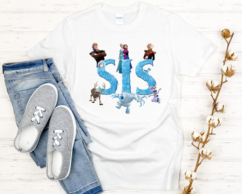 May include: White t-shirt featuring the word "SIS" in blue, with cartoon characters from a popular animated movie. The shirt is paired with blue jeans and gray sneakers.