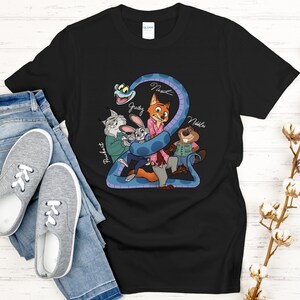 Puede incluir: Camiseta negra con un gr&aacute;fico de dibujos animados de personajes de una pel&iacute;cula. El dise&ntilde;o incluye una serpiente azul y personajes de animales con nombres. La camiseta se combina con vaqueros azules y zapatillas grises.