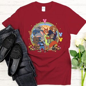 Peut inclure: T-shirt bordeaux avec une illustration de dessins anim&eacute;s des personnages de Zootopie, dont Judy Hopps et Nick Wilde. Le design est pr&eacute;sent&eacute; avec un jean noir et des chaussures.
