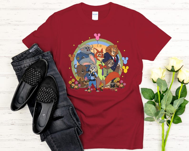 Peut inclure: T-shirt bordeaux avec une illustration de dessins anim&eacute;s des personnages de Zootopie, dont Judy Hopps et Nick Wilde. Le design est pr&eacute;sent&eacute; avec un jean noir et des chaussures.