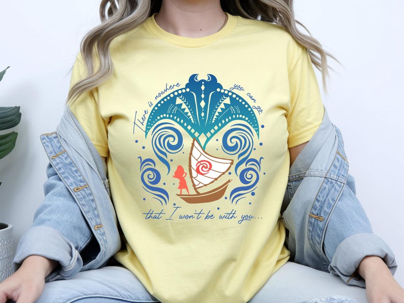 Op de afbeelding: Lichtgeel T-shirt met een grafisch ontwerp met een boot met een wit zeil, een silhouet van een persoon en wervelende blauwe golven. Het ontwerp bevat de tekst "There is nowhere you can go that I won't be with you..."