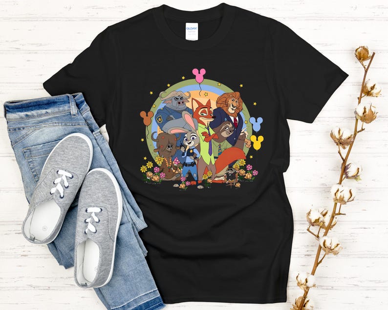 Peut inclure: T-shirt noir avec un motif color&eacute; de personnages de dessins anim&eacute;s, un arc-en-ciel et des fleurs. Le design est pr&eacute;sent&eacute; sur un fond noir. Le t-shirt est associ&eacute; &agrave; un jean bleu et des baskets grises.