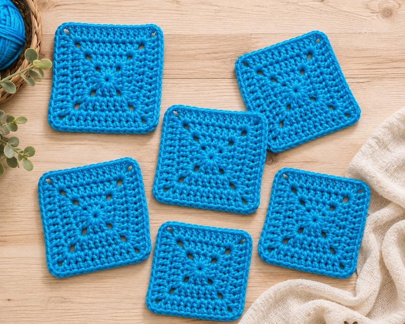 May include: Five square crochet coasters in a vibrant bright blue yarn. Each coaster features a central star-like pattern with openwork stitches radiating outward toward the edges, creating a consistent geometric design across all five pieces.