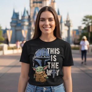 May include: Black t-shirt with a graphic of a helmet, a small green creature, and the phrase "THIS IS THE WAY" in white. The design is inspired by a popular science fiction series.
