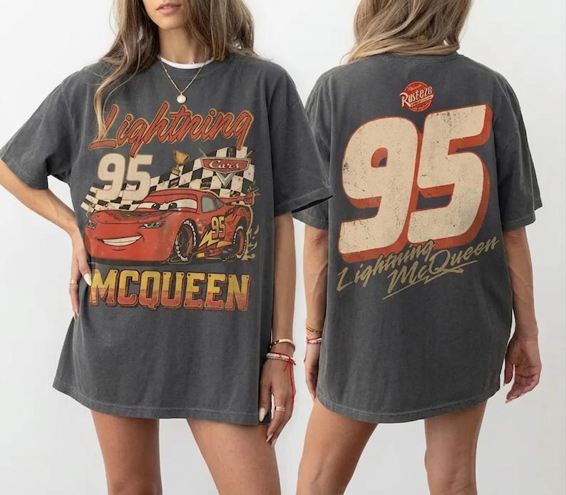 Puede incluir: Camiseta gris oscuro con un dise&ntilde;o de Rayo McQueen de la pel&iacute;cula Cars. El dise&ntilde;o frontal incluye el n&uacute;mero 95, una bandera a cuadros y el nombre McQueen. La parte trasera de la camiseta tambi&eacute;n muestra el n&uacute;mero 95 y el nombre Rayo McQueen.