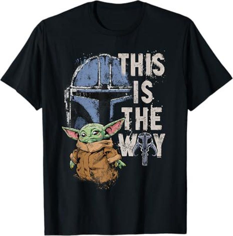 May include: Black t-shirt with a graphic of a green alien character, a blue helmet, and the text "THIS IS THE WAY". The alien has large ears and wears a brown cloak.