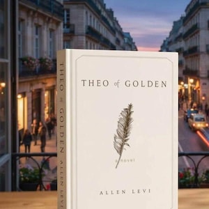 May include: A hardcover book titled "THEO of GOLDEN" by Allen Levi. The book cover is off-white with the title in black, a feather illustration, and the word "a novel". The book is set against a blurred city backdrop.