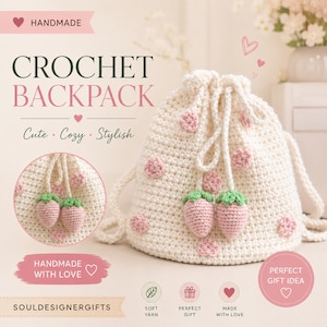 May include: A cream-coloured crochet drawstring backpack featuring pink circular polka dots and two dangling strawberry-shaped charms with green tops. The bag has thick braided straps and is crafted from yarn with a textured, handmade appearance.