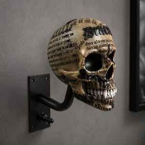 Puede incluir: Una escultura de calavera beige con detalles y texto en negro, montada sobre un soporte de metal negro. La calavera tiene un tema gótico. El texto incluye la palabra "Souls".