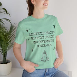 Camiseta de rana con teoría de la conspiración, camiseta para encubrir objetos brillantes, camiseta de humor sobre TDAH y criaturas críptidas