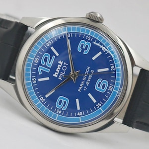 May include: A silver-toned wristwatch with a blue face and black leather band. The watch face features large white numerals at the 12, 3, 6, and 9 o'clock positions, with smaller markers around the perimeter. The text "PARA SHOCK 17 JEWELS" is visible.