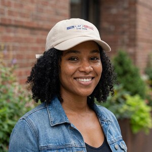 May include: A beige baseball cap with the text "CTRL ALT" and "1776-2026" in red and blue. The cap is worn by a person wearing a denim jacket.