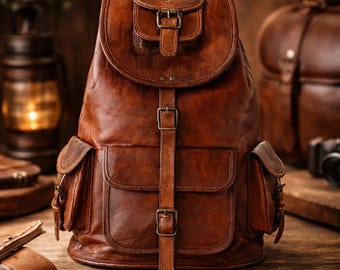 Può includere: Uno zaino in pelle marrone dotato di manico superiore, patta principale con chiusura a fibbia e una tasca più piccola con fibbia sulla patta. La borsa include due tasche laterali e una grande tasca frontale, fissate con cinghie e fibbie.