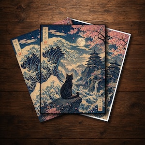Può includere: Tre stampe artistiche con un'illustrazione in stile giapponese di un gatto nero appollaiato su una roccia, che domina un paesaggio con un castello, fiori di ciliegio e una luna piena. Le stampe hanno una combinazione di colori blu, bianco e rosa.