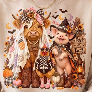 Peut inclure: Un sweat-shirt beige avec une illustration représentant une vache Highland en fantôme, un poulet en squelette et un cochon en sorcière. Le motif inclut des citrouilles, des tournesols, une lanterne et le texte Trick or Treat et Spooky.