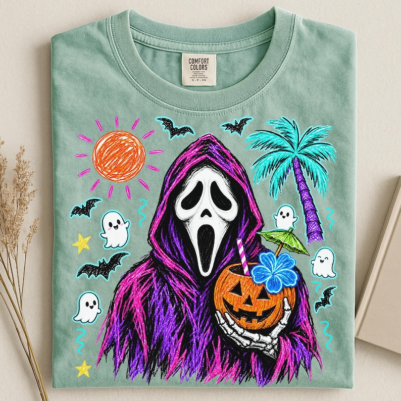 May include: A sage green t-shirt featuring a graphic of a hooded figure in a white mask holding a jack-o'-lantern drink with a straw and umbrella. The design includes a scribbled orange sun, blue palm tree, bats, stars, and small white ghosts.