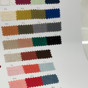 May include: A fabric swatch card featuring a variety of colors, including white, burgundy, green, navy, beige, gold, orange, pink, red, and blue. Each color is labeled with a number.