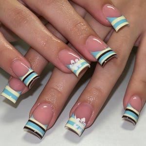 Unghie finte personalizzate da applicare, french manicure a righe blu e crema, piccola stampa floreale bianca lucida, fatte a mano, carine, casual, estive, per tutti i giorni.
