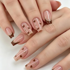 Unghie finte personalizzate / Marrone con bordo dorato francese e stampa a cuoricini, unghie riutilizzabili dai toni caldi e neutri per uno stile casual autunnale.