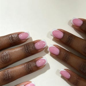 Pode incluir: Um conjunto de unhas artificiais de formato quadrado com um design clássico de manicure francesa. Cada unha tem uma base rosa brilhante e translúcida com uma ponta branca opaca e definida, dispostas para mostrar o formato uniforme.