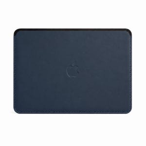 Può includere: Una custodia rettangolare blu navy scuro con angoli arrotondati e un bordo superiore nero. La superficie frontale presenta un logo Apple impresso al centro. La custodia è realizzata con cuciture visibili lungo i bordi perimetrali.