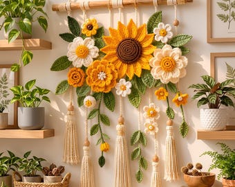 Peut inclure: Une décoration murale composée de tournesols, marguerites et soucis crochetés dans des tons jaune, blanc et orange avec des feuilles vertes. L'ensemble est suspendu à une tige en bois par des cordons crème, agrémenté de perles et de pompons.
