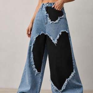 May include: High-waisted wide-leg jeans featuring a light blue denim base with contrasting black denim panels. The black panels are integrated into the front with raw, frayed edges along the seams, creating a distinct layered appearance.