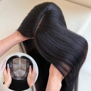 May include: A black hair topper featuring straight, smooth strands and a central part. The inset circular image displays the underside of the hairpiece, showing a sheer lace base with four metal pressure-sensitive clips attached for secure placement.