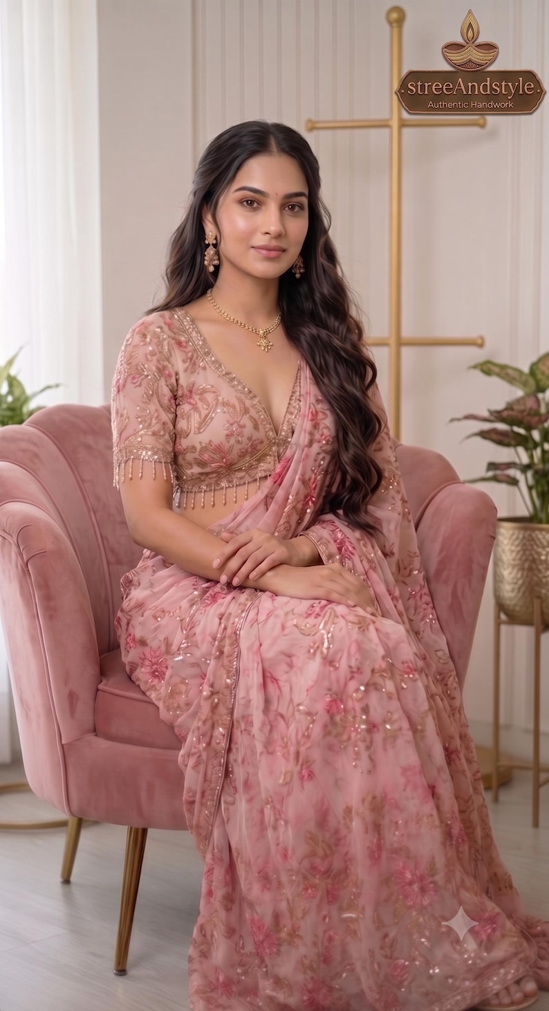 May include: A light pink saree featuring intricate floral embroidery with sequins and beads. The blouse has a deep V-neckline, short sleeves with beaded fringe trim, and matching floral patterns. The logo streeAndstyle Authentic Handwork is visible.
