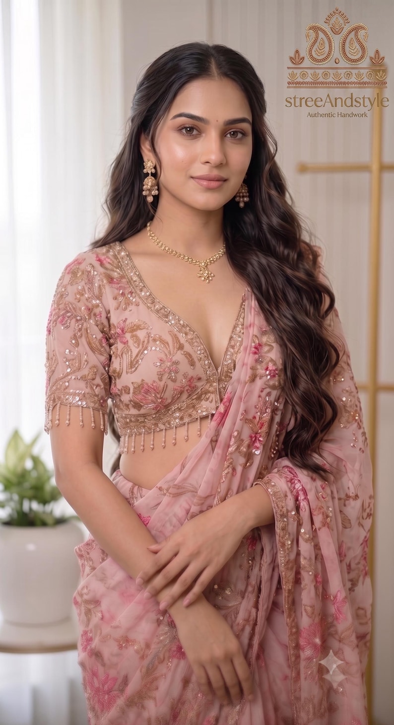 May include: A light pink saree featuring intricate gold and pink floral embroidery, sequins, and a matching blouse with short sleeves and beaded fringe trim. The garment includes the text streeAndstyle Authentic Handwork in the upper corner.